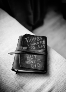 Eine schwarz-weiße Abbildung eines ledergebundenen Tagebuchs, das auf einem Tisch liegt. Auf dem Einband steht in heller Schrift: Things I wanted to say but never did.